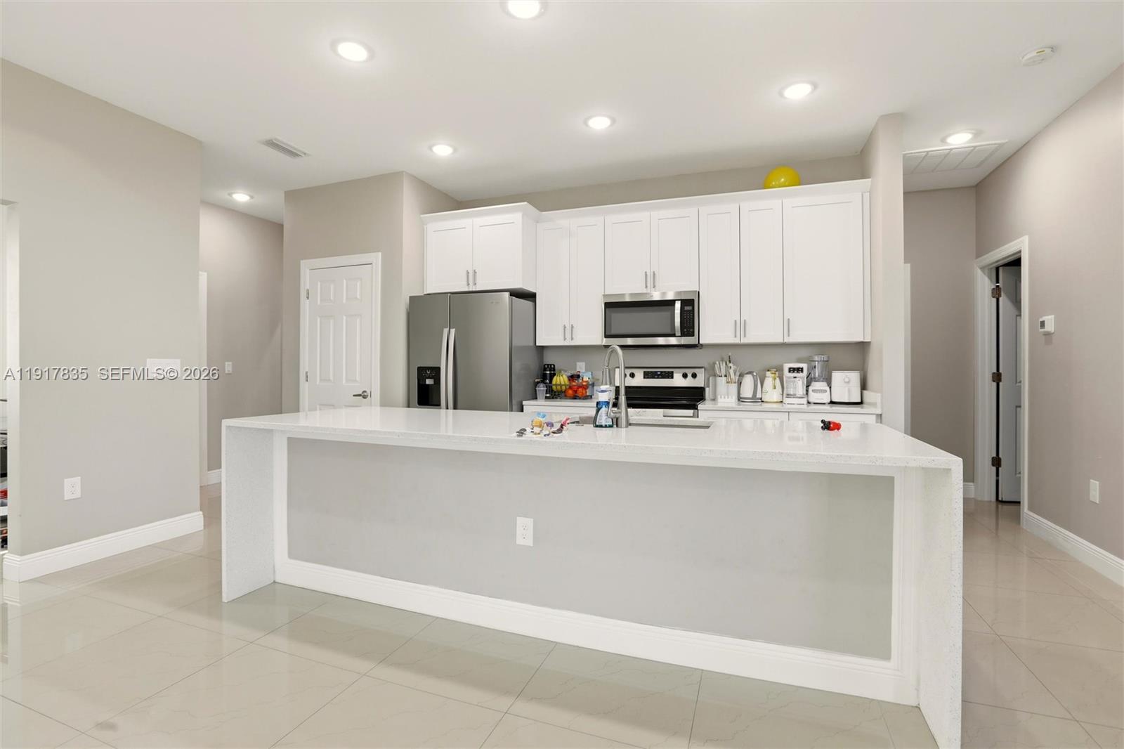 2908 9th Street Southwest Lehigh Acres, FL 33976 - Photo 11 of 44 a kitchen with kitchen island a white counter top space cabinets and stainless steel appliances