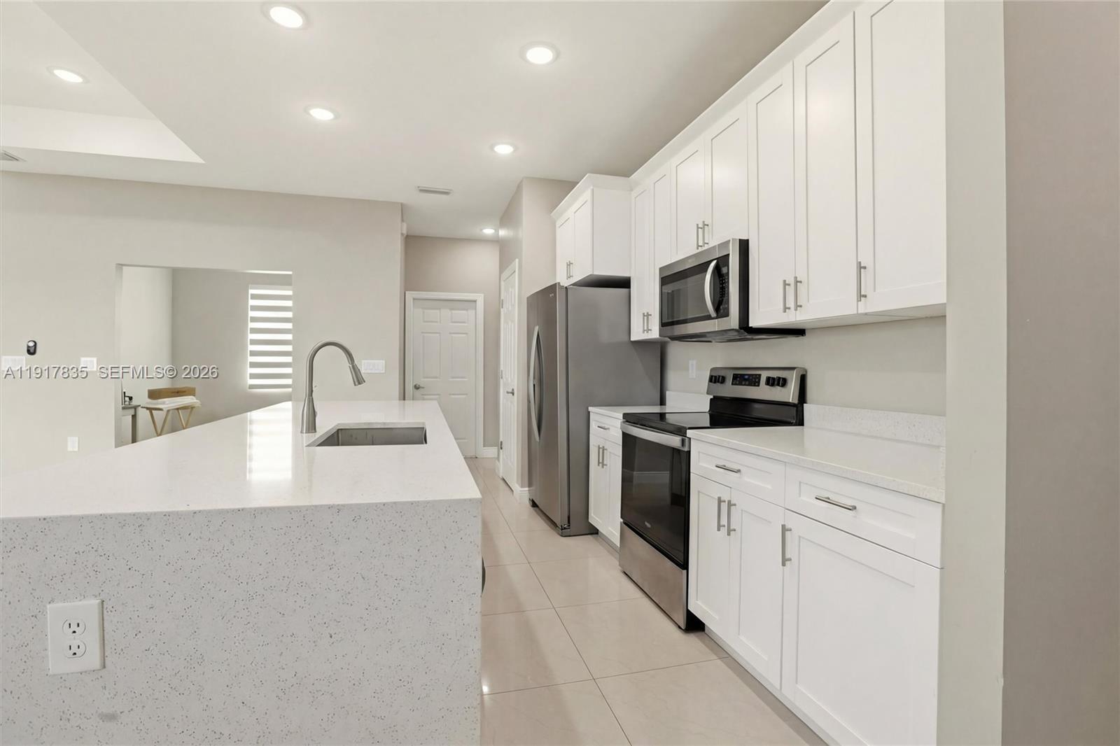2908 9th Street Southwest Lehigh Acres, FL 33976 - Photo 8 of 44 a kitchen with stainless steel appliances a refrigerator sink and white cabinets