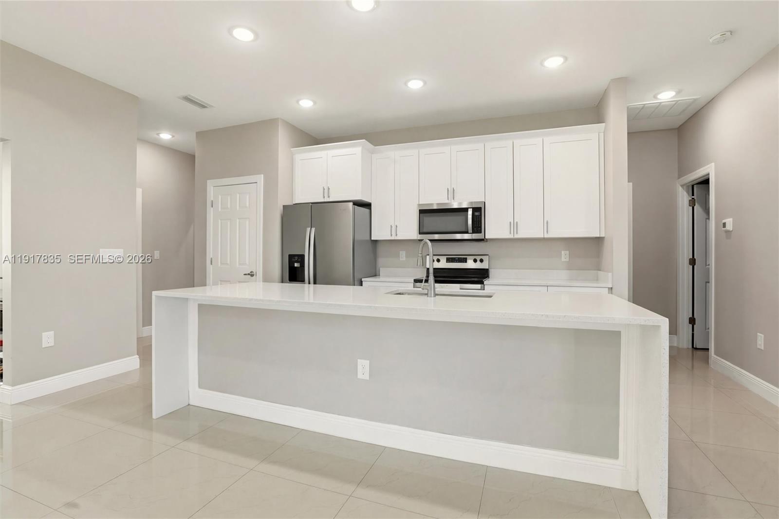 2908 9th Street Southwest Lehigh Acres, FL 33976 - Photo 10 of 44 a kitchen with kitchen island a refrigerator sink and cabinets