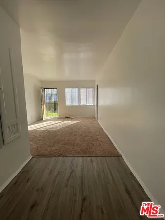 a view of hallway with wooden floor and cabinet