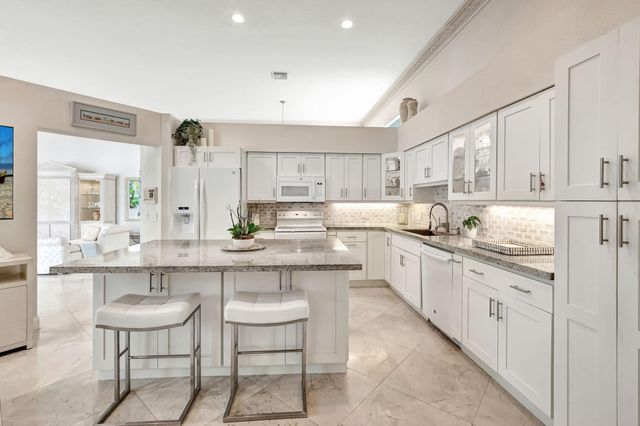 a large kitchen with kitchen island white cabinets and stainless steel appliances
