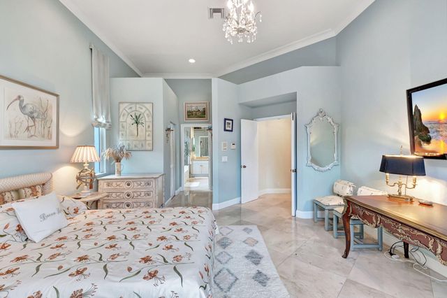 a bedroom with a bed a chandelier and mirror
