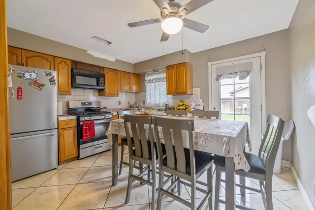 a kitchen with stainless steel appliances granite countertop a stove a refrigerator a microwave a dining table and chairs with wooden floor