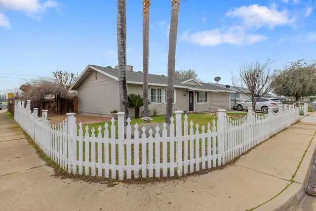 a view of a house with a small yard and wooden fence