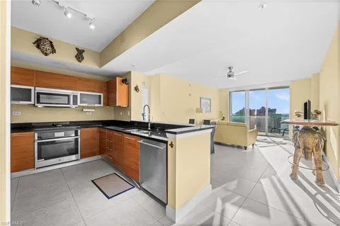 a kitchen with stainless steel appliances granite countertop a refrigerator a stove and a sink with dishwasher next to a window