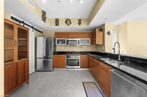 a large kitchen with stainless steel appliances granite countertop a refrigerator and a sink