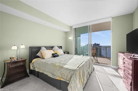 a bedroom with a bed and a flat tv screen on dresser