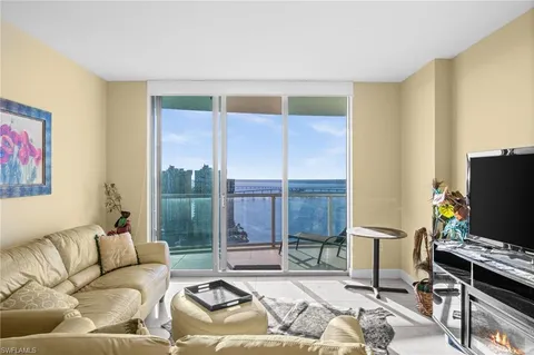 a living room with furniture a flat screen tv and a floor to ceiling window