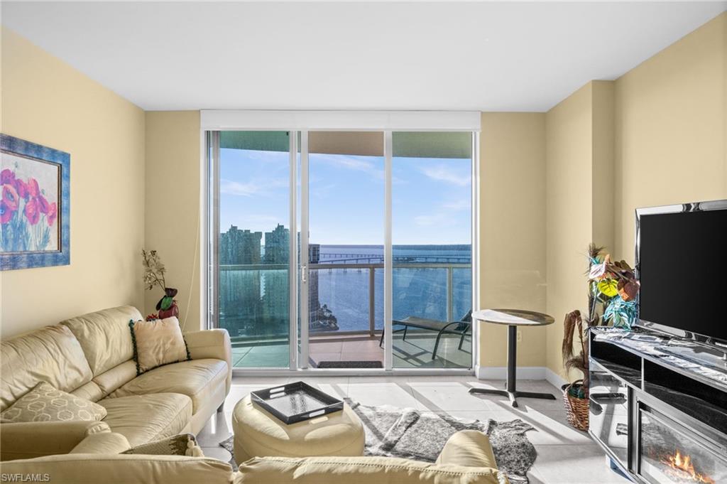 3000 Oasis Grand Boulevard, Unit 2702 Fort Myers, FL 33916 - Photo 5 of 34 a living room with furniture a flat screen tv and a floor to ceiling window