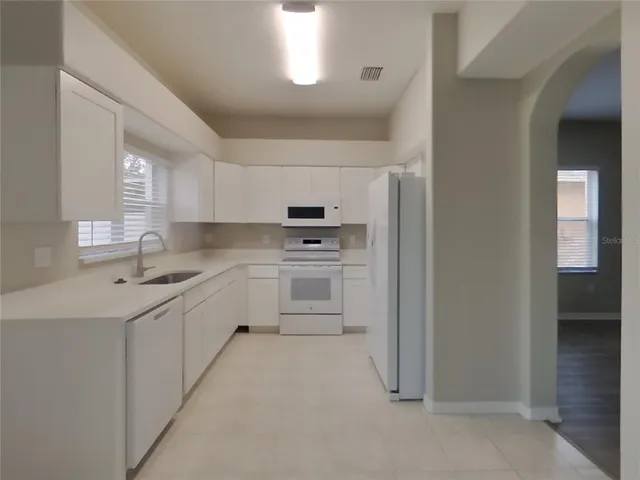a kitchen with white cabinets and white appliances