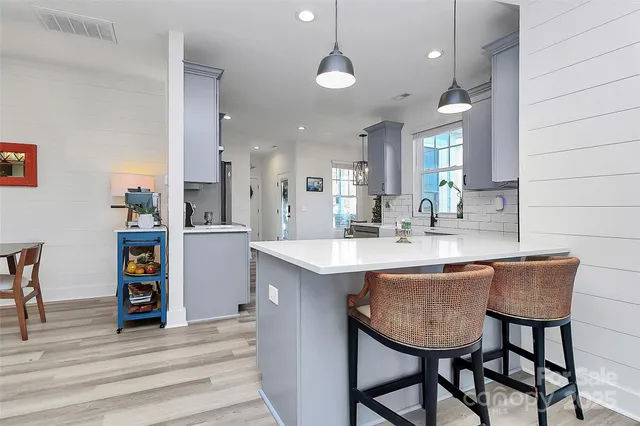 a kitchen with stainless steel appliances granite countertop a table chairs sink and cabinets