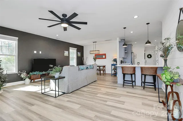 a living room with furniture kitchen view and a wooden floor