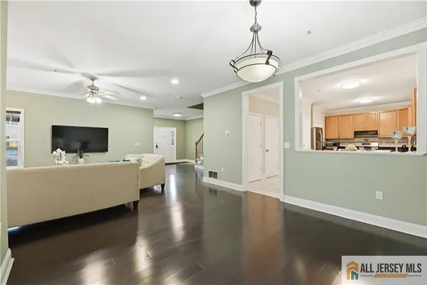 a living room with couches a flat screen tv and kitchen view