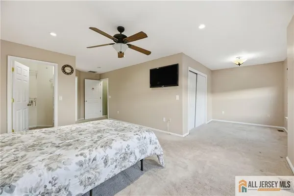 a spacious bedroom with a bed and a flat screen tv