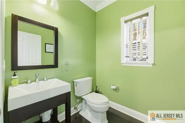 a bathroom with a toilet a sink a mirror and a window