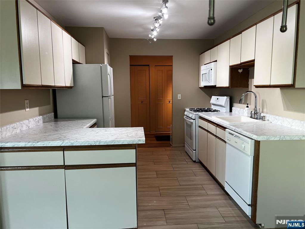 34 Riverview Court, Unit 34 Secaucus, NJ 07094 - Photo 4 of 16 a kitchen with kitchen island granite countertop wooden cabinets a sink a stove and a refrigerator