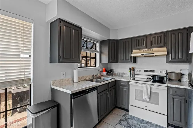 a kitchen with stainless steel appliances granite countertop a sink stove refrigerator and cabinets