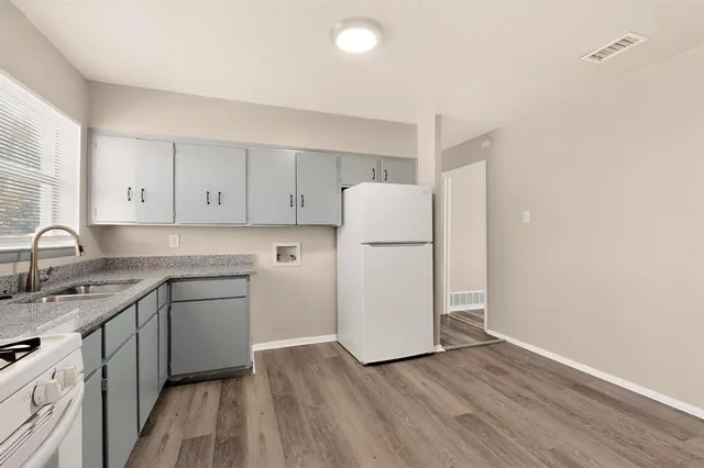 a kitchen with wooden cabinets sink and white appliances