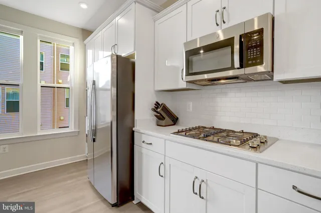 a kitchen with stainless steel appliances white cabinets and a stove top oven