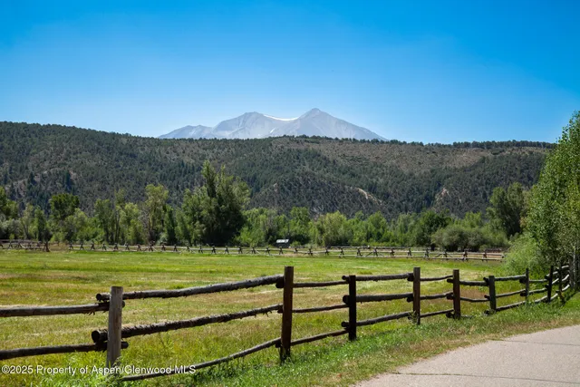 a view of a green field with mountains in the background