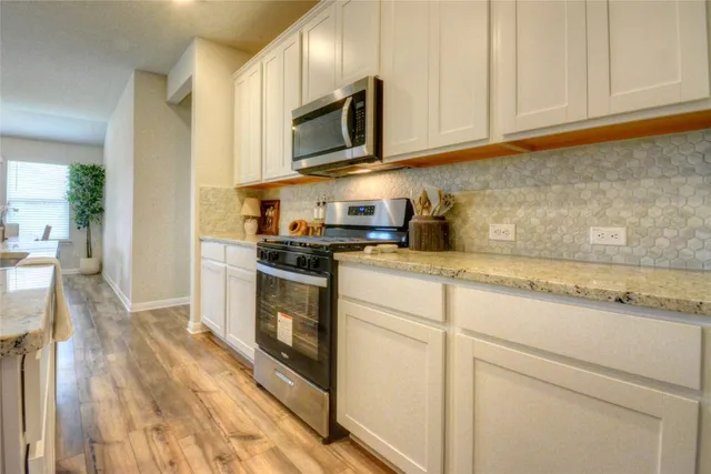 a large kitchen with stainless steel appliances a stove a sink a microwave a refrigerator and cabinets