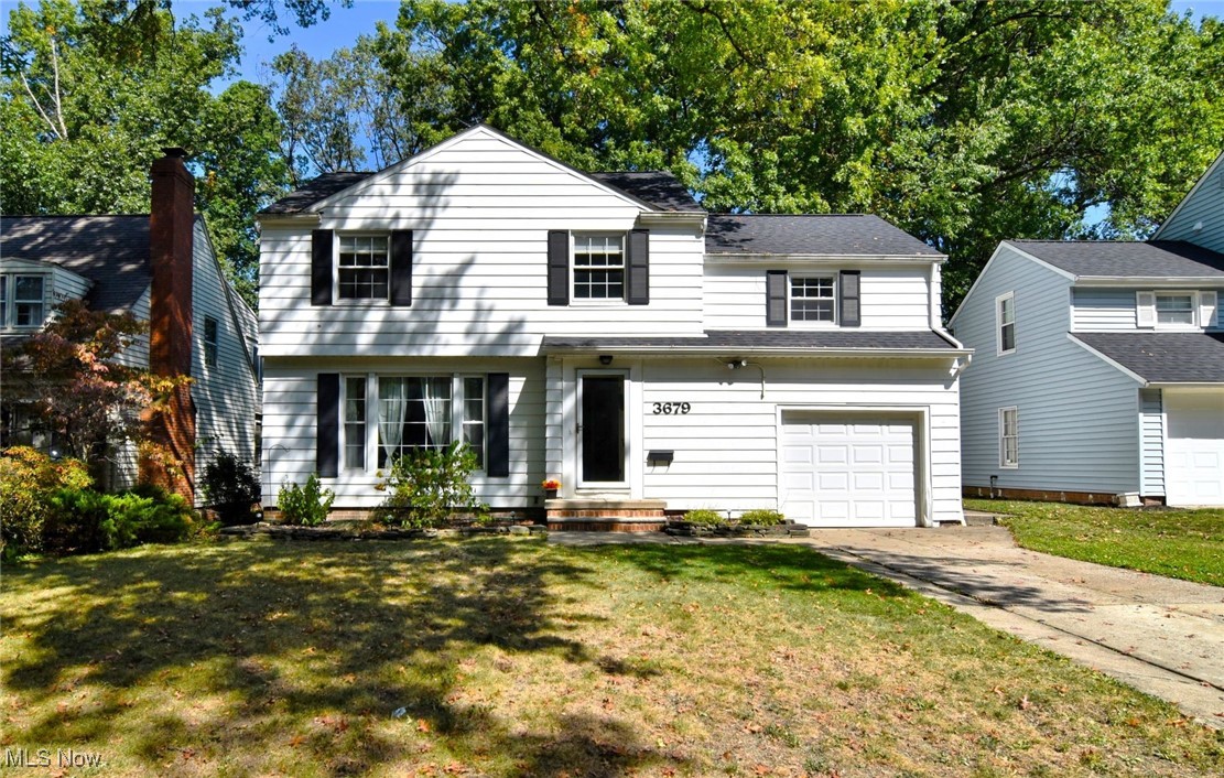 View of front facade featuring a front lawn, driveway, and an attached garage