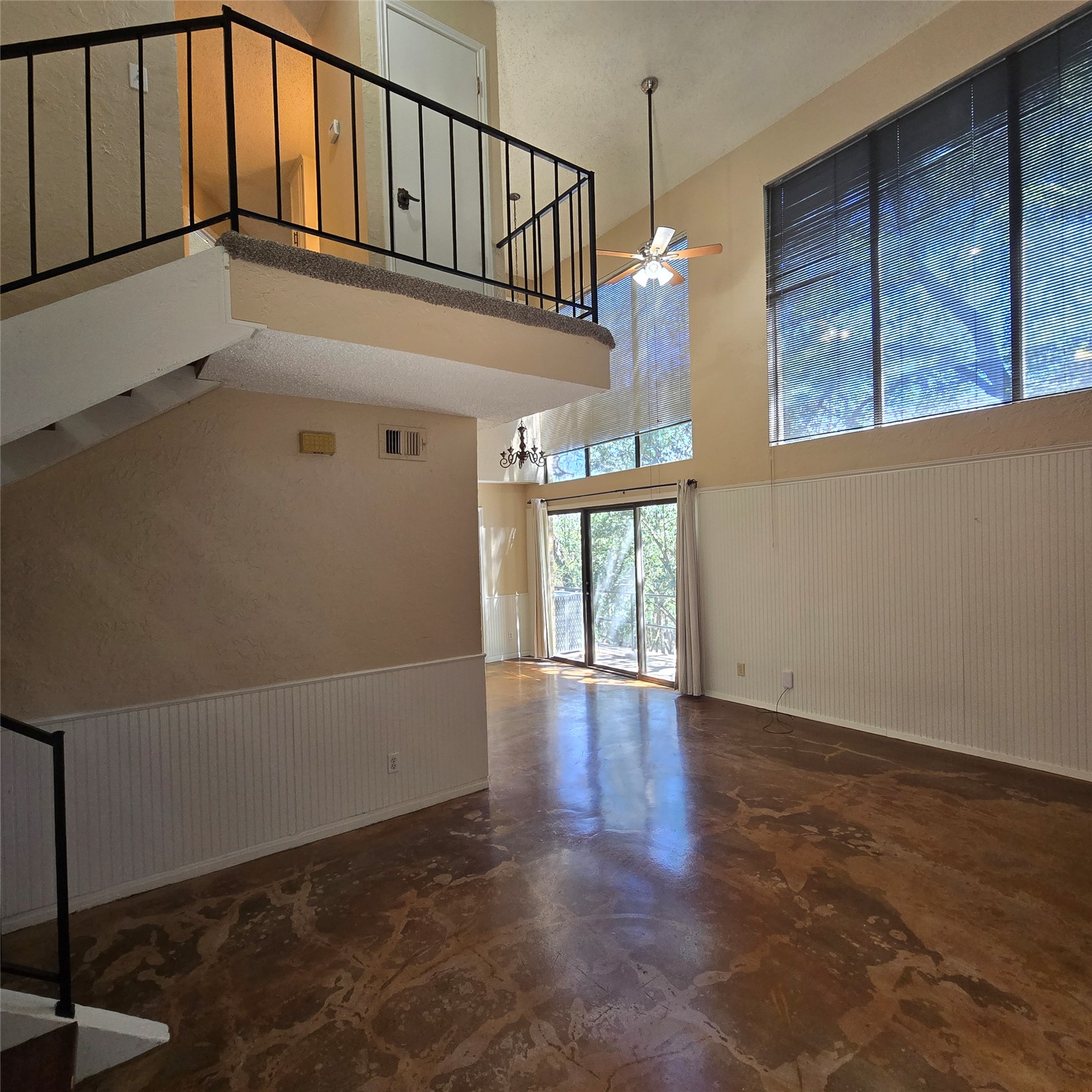 801 Ranch Road 12 San Marcos, TX 78666 - Photo 4 of 21 Unfurnished living room with a wainscoted wall, ceiling fan, a high ceiling, wood walls, and concrete floors