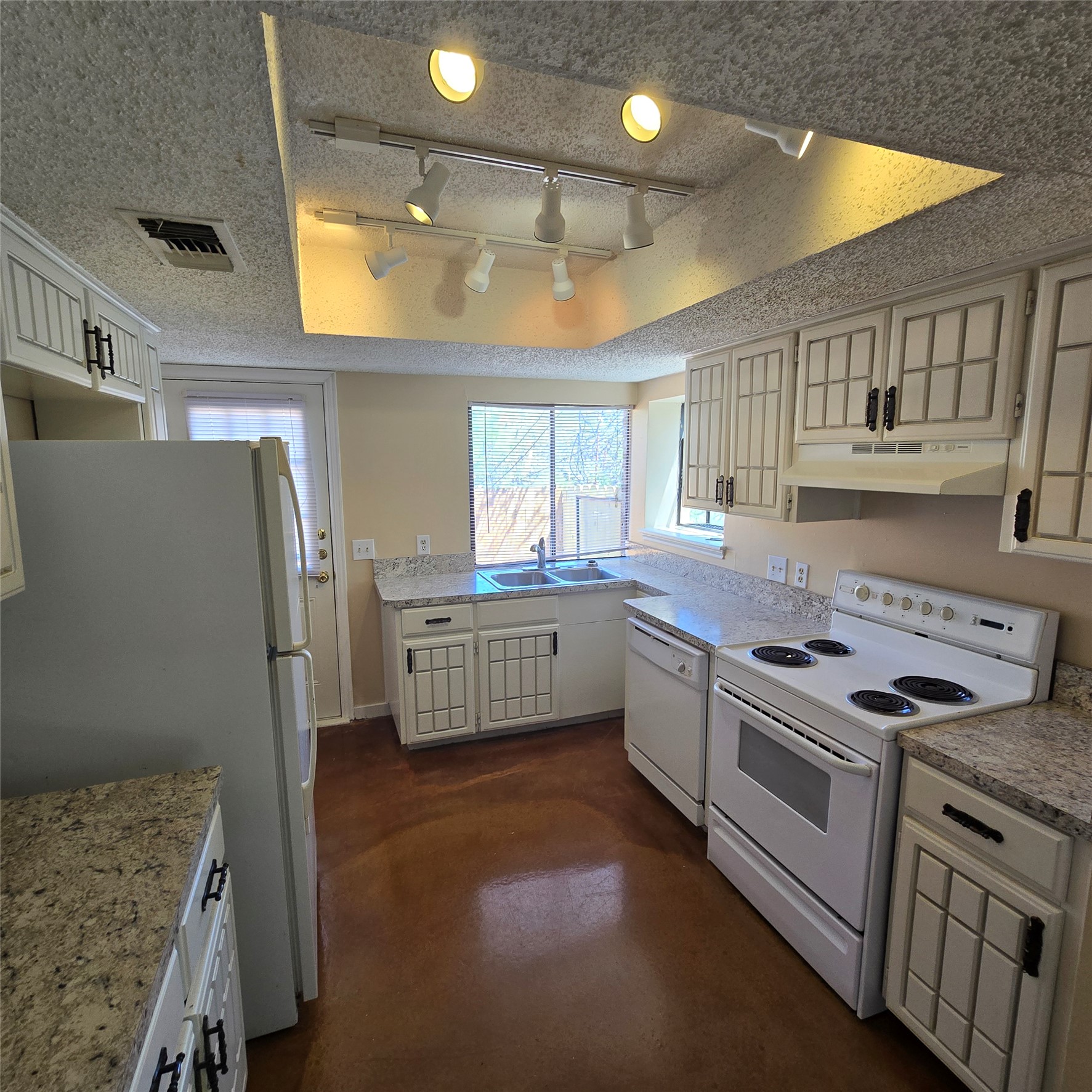 801 Ranch Road 12 San Marcos, TX 78666 - Photo 6 of 21 Kitchen featuring white appliances, light countertops, a textured ceiling, finished concrete flooring, and track lighting