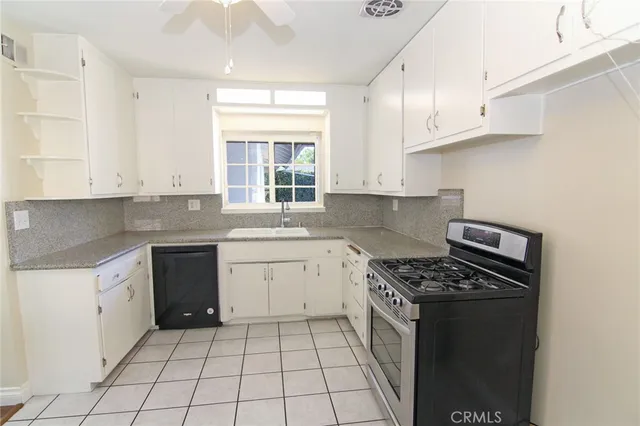 a kitchen with granite countertop a stove sink and cabinets