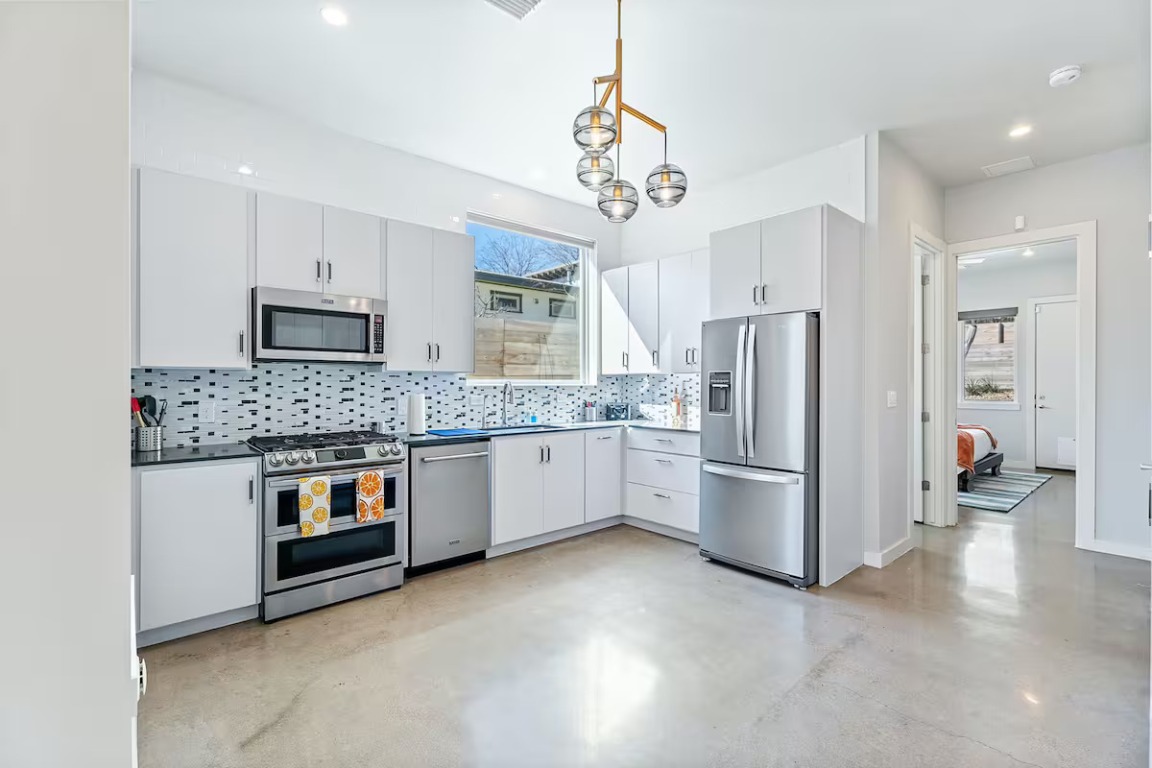4314 Jinx Avenue, Unit A Austin, TX 78745 - Photo 21 of 40 Kitchen with stainless steel appliances, concrete floors, tasteful backsplash, pendant lighting, and white cabinetry