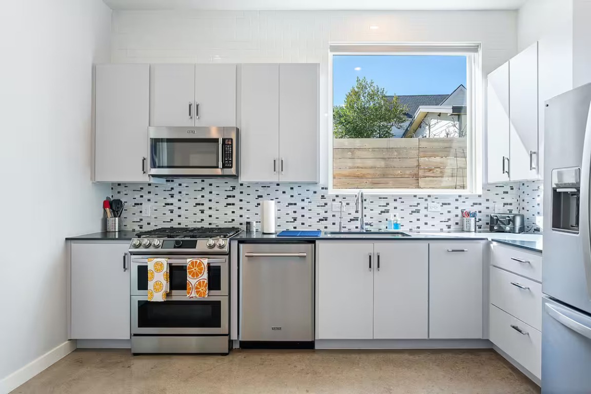4314 Jinx Avenue, Unit A Austin, TX 78745 - Photo 22 of 40 Kitchen with appliances with stainless steel finishes, backsplash, white cabinets, and dark countertops
