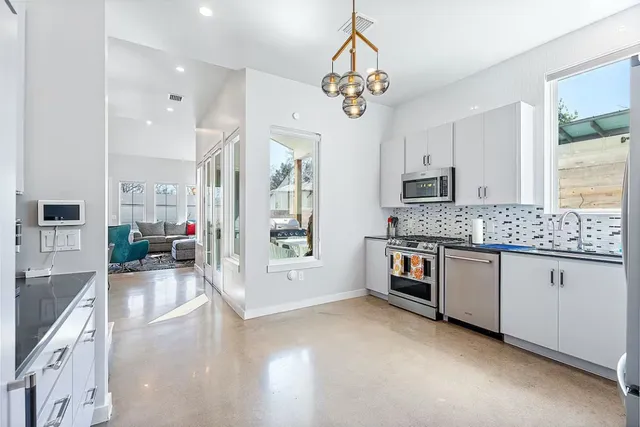 a large white kitchen with stainless steel appliances granite countertop a lot of counter space and wooden floor