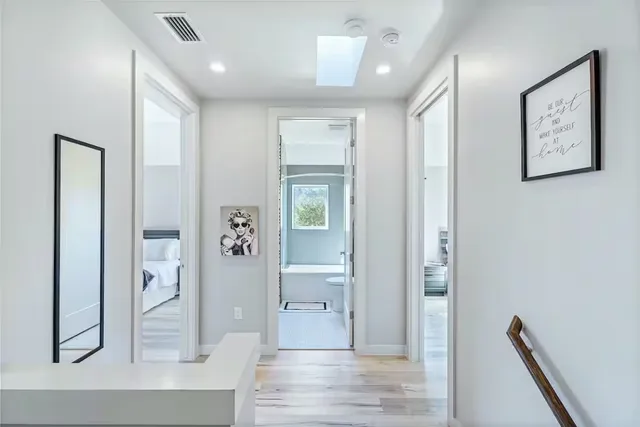 a view of a hallway with wooden floor and a living room
