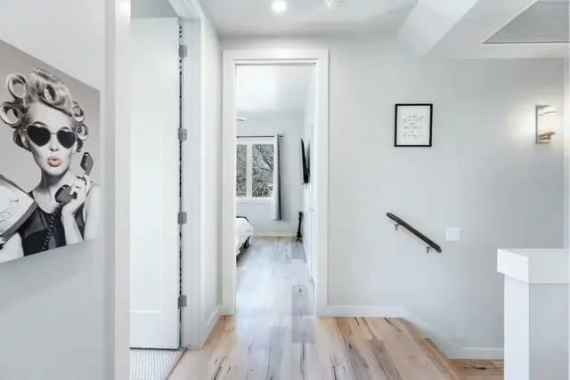 a view of a hallway with wooden floor and a bathroom