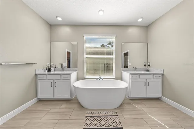 a spacious bathroom with a double vanity sink a mirror and a bathtub