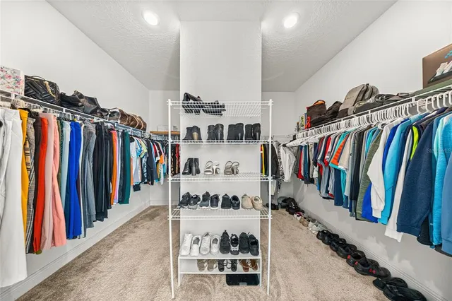 a view of walk in closet with clothes and shoes