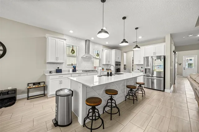 a kitchen with a refrigerator a stove and white cabinets with wooden floor