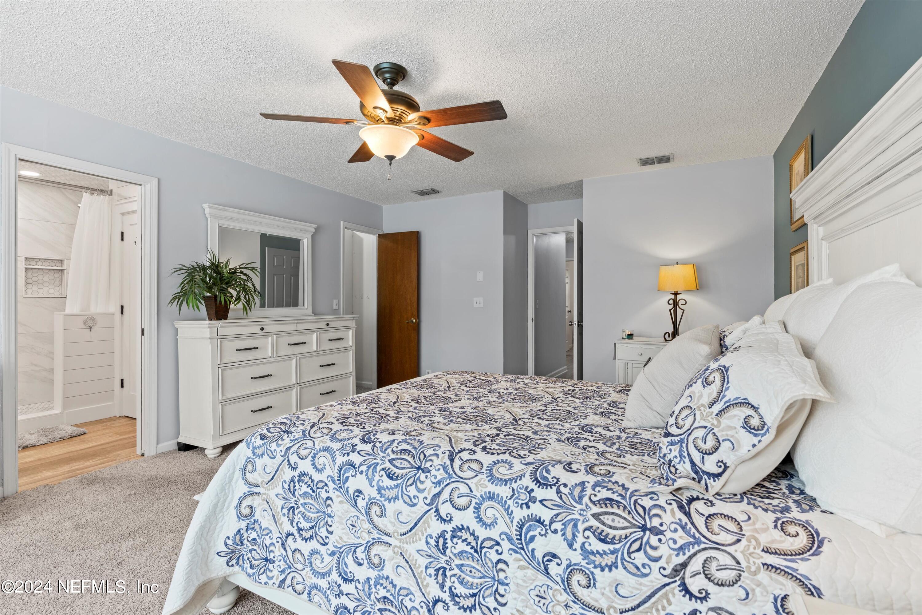 1474 Fruit Cove Forest Road North St. Johns, FL 32259 - Photo 19 of 36 a bedroom with a large bed and a chandelier