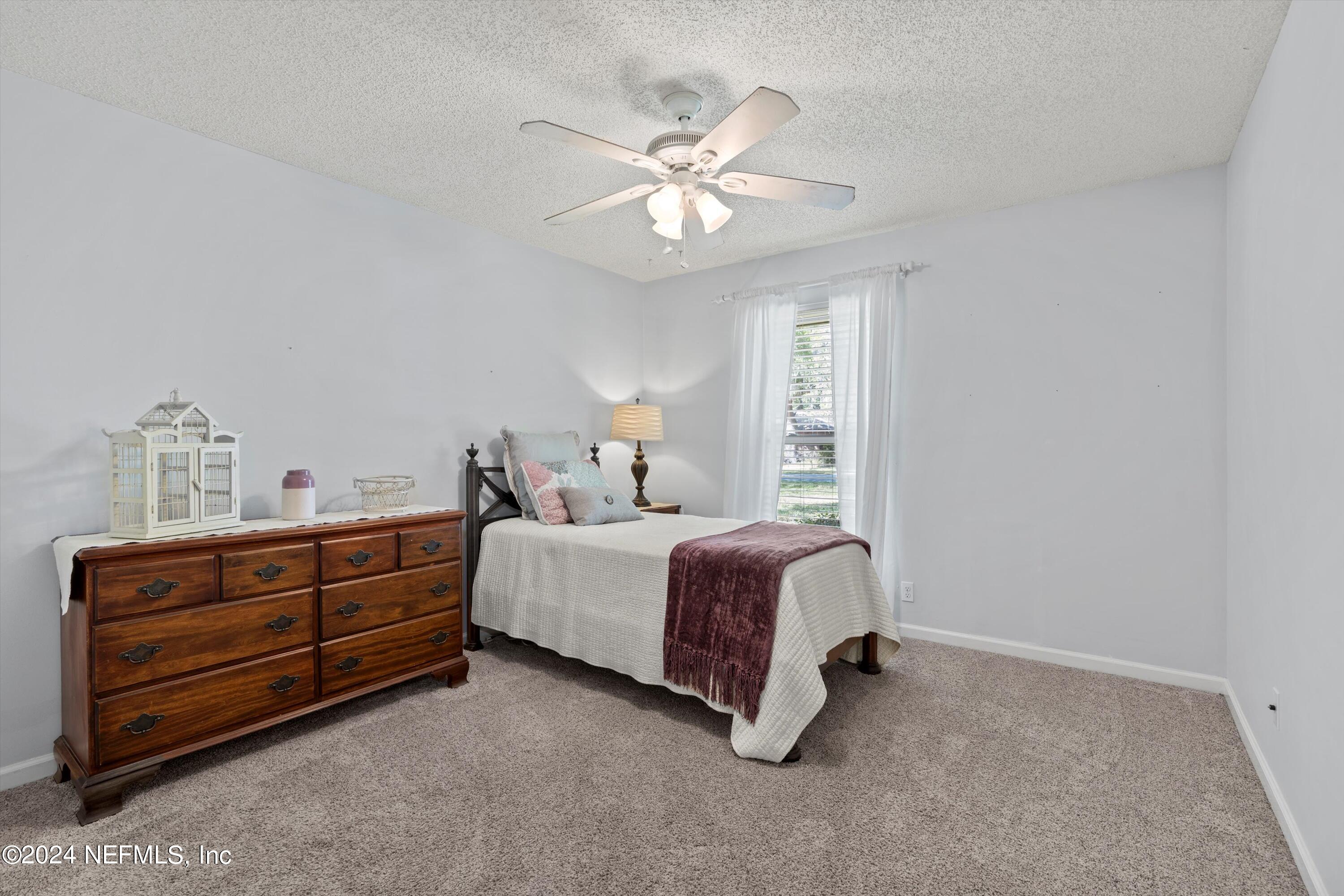 1474 Fruit Cove Forest Road North St. Johns, FL 32259 - Photo 25 of 36 a spacious bedroom with a bed and a chandelier