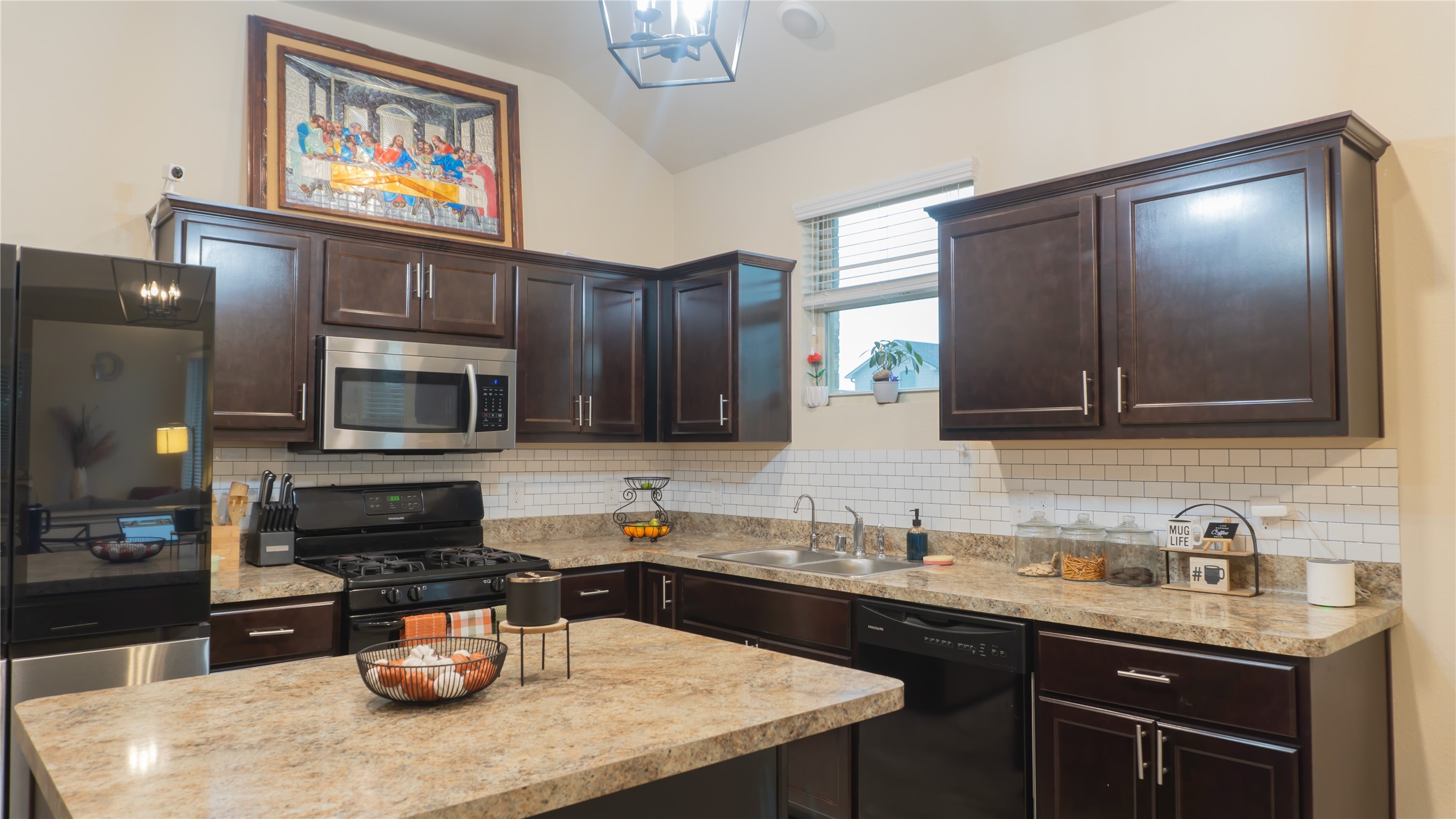 20511 Rimini River Way Katy, TX 77449 - Photo 2 of 30 This beautifully updated kitchen showcases dark wood cabinetry, stainless steel appliances, a sleek tile backsplash, and generous countertop space. A window above the sink brings in soft natural light, creating a warm and inviting atmosphere.