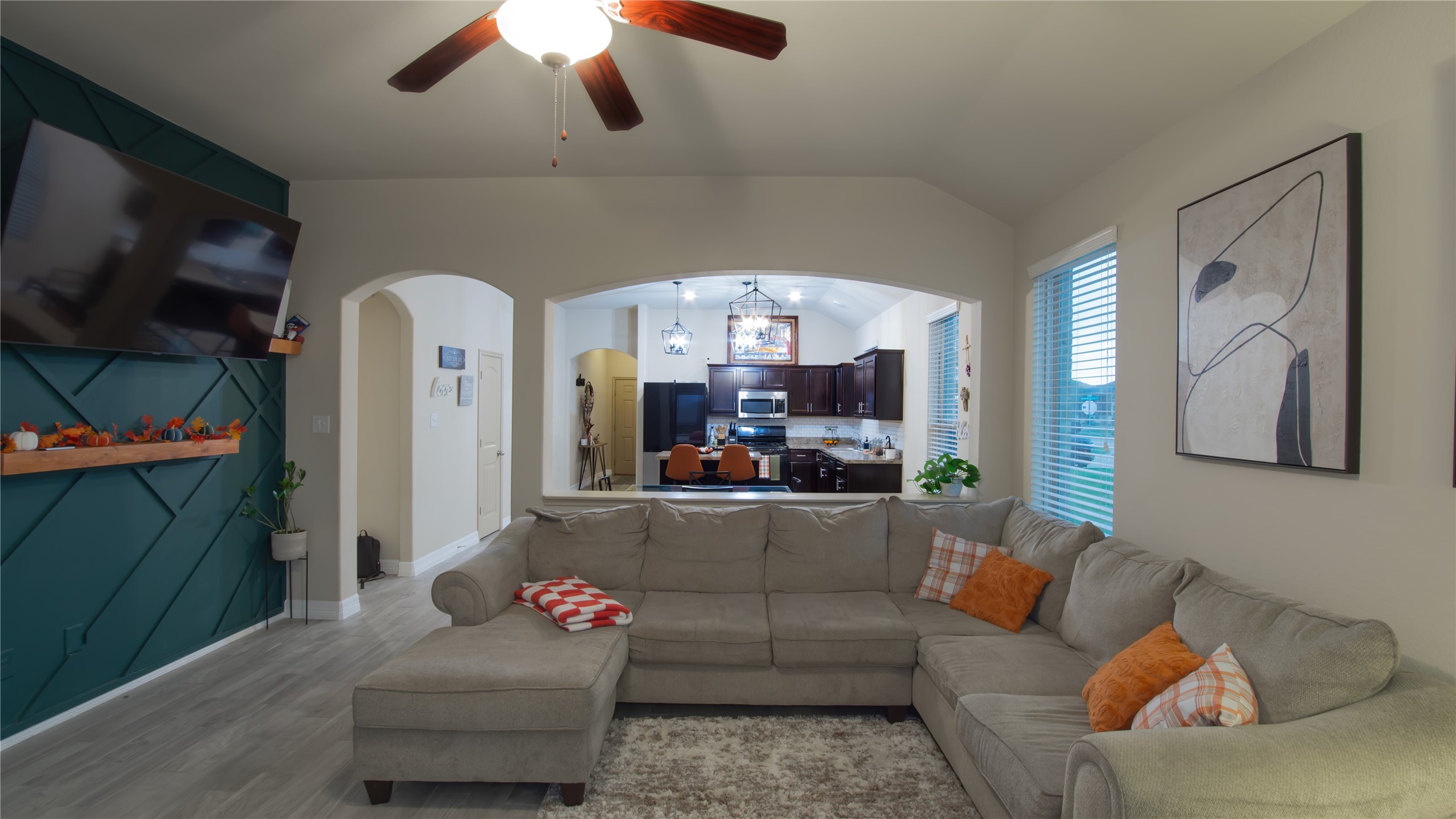20511 Rimini River Way Katy, TX 77449 - Photo 4 of 30 This inviting living room combines modern style with functionality, featuring a ceiling fan and an open layout that connects effortlessly to the bright kitchen with dark cabinetry and stainless steel appliances, creating a welcoming space for gatherings.