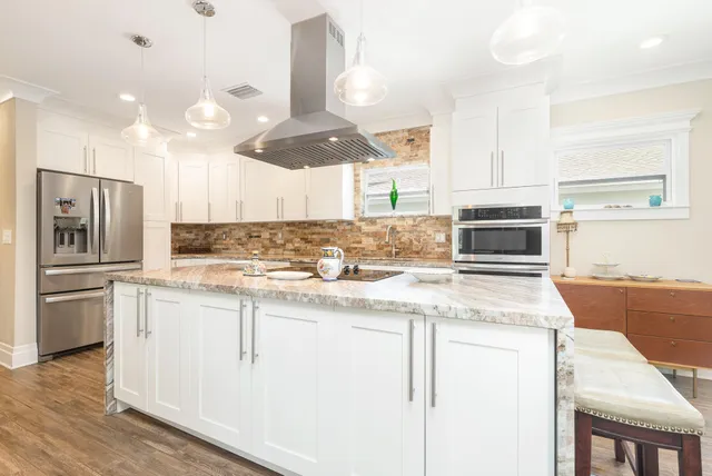 a kitchen with stainless steel appliances kitchen island granite countertop a stove a sink and a refrigerator