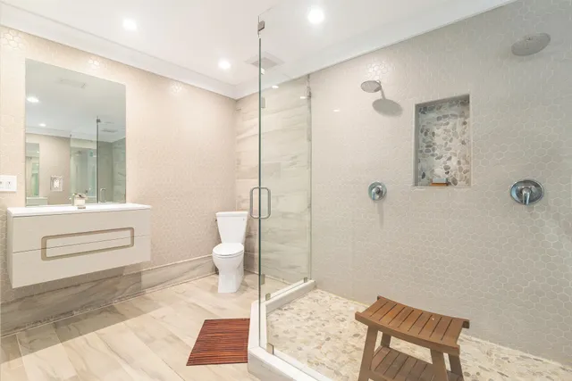 a bathroom with a sink a toilet a mirror and shower