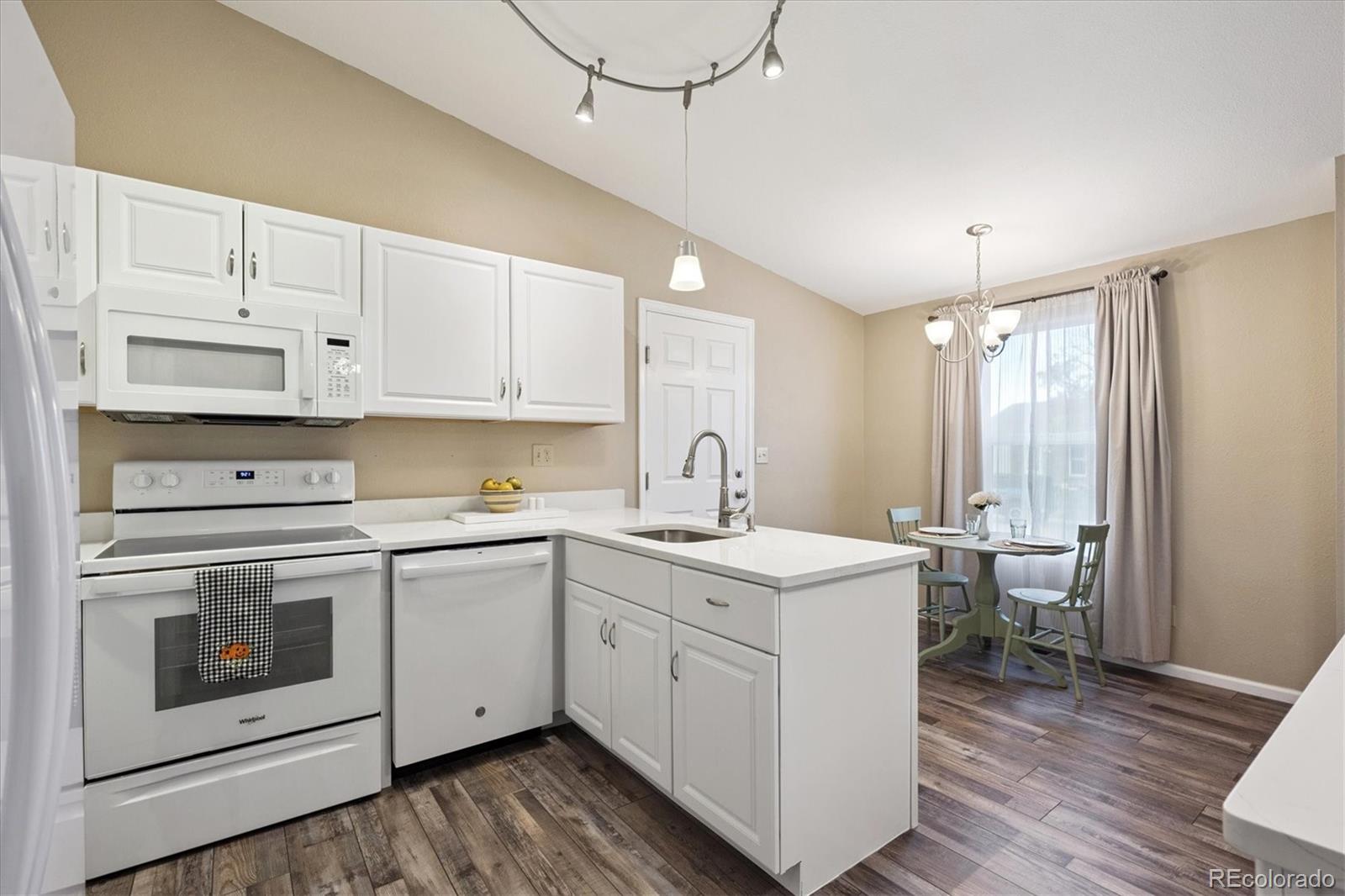 704 Madison Way Bennett, CO 80102 - Photo 11 of 29 a kitchen with a sink stove and white cabinets with wooden floor