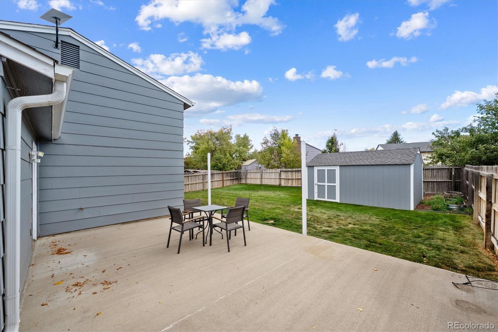 704 Madison Way Bennett, CO 80102 - Photo 20 of 29 a view of a patio with table and chairs with wooden fence