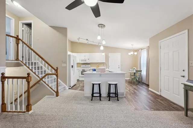 a kitchen with a sink stove and white cabinets with wooden floor