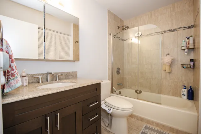 a bathroom with a granite countertop sink toilet mirror and shower