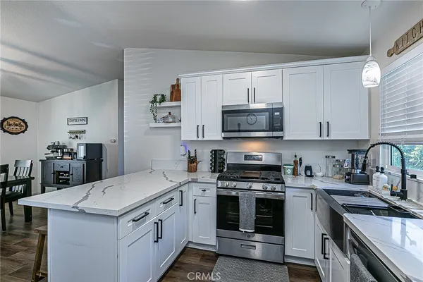 a kitchen with stainless steel appliances granite countertop a stove top oven a sink a counter space and cabinets