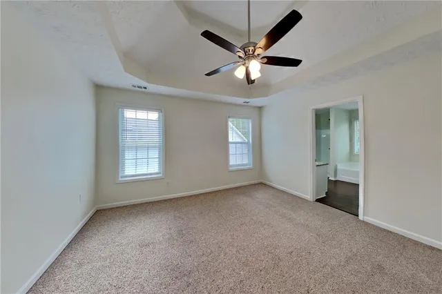 an empty room with windows and fan