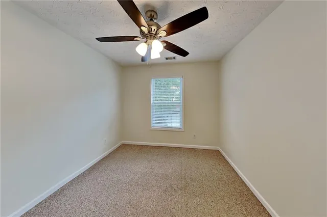 an empty room with a window and a ceiling fan
